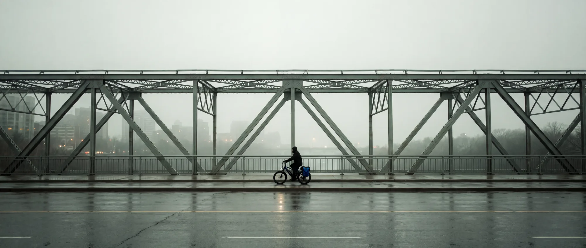 A lone commuter on an empty six-lane bridge under flat overcast light